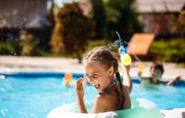 cheerful children playing waterguns rejoicing jumping swimming pool